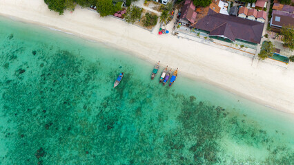 Aerial view of traditional Thai long tail boats at a beach at Koh Phi Phi island, Krabi, Thailand. Tropical paradise white sand beach with no people, turquoise waters of Andaman sea. 