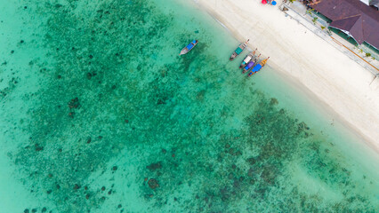 Aerial view of traditional Thai long tail boats at a beach at Koh Phi Phi island, Krabi, Thailand. Tropical paradise white sand beach with no people, turquoise waters of Andaman sea. 