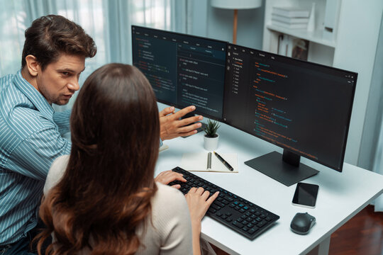 Team skilled developers program coding discussing creative website planning software project on two screen monitor's full stack data analyzing design at office with back side view concept. Postulate.