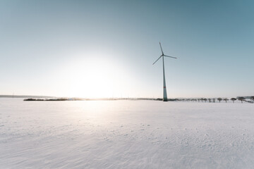 Erneuerbare Energie im Winter: Einsames Windrad in verschneiter Landschaft bei Sonnenuntergang