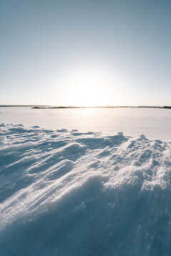 Winterzauber bei Sonnenuntergang: Unberührte Schneelandschaft mit schimmernden Wehen und strahlendem Licht