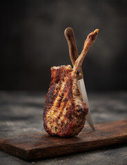 Grilled pork meat with bone and knife on wooden board - 761813233
