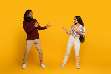 Man and woman engaging in playful pointing on yellow