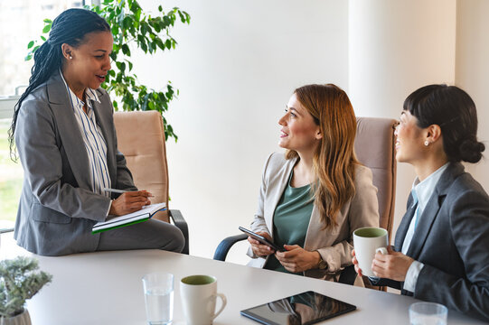 A diverse group of multi-ethnic businesswomen sit in the office and have a conversation. They engage in discussions, reflecting their entrepreneurial spirit and collaboration