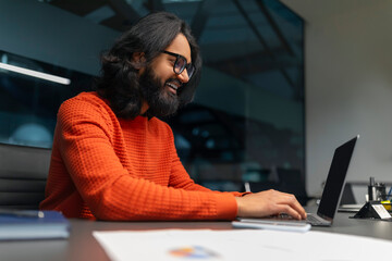Joyful man typing on a laptop in the office