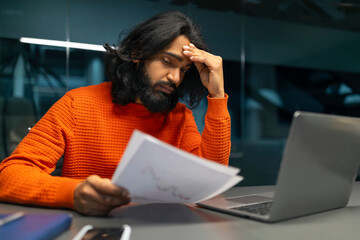 Man with headache over paperwork