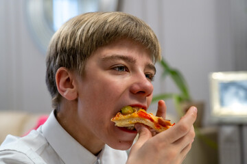 Teen boy sitting and eating a slice of pizza