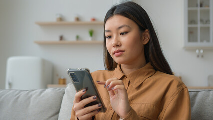 Korean chinese multiracial woman use smartphone application surfing internet social media pensive...