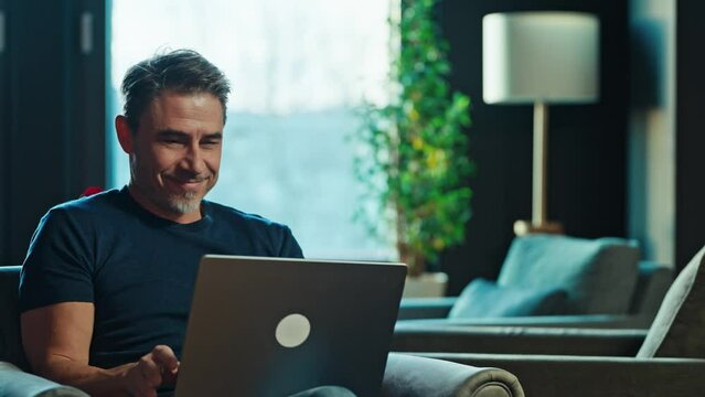 Casual mid adult man with laptop computer in home office, banking online, remote working. Portrait of older bearded guy thinking. Businessman, entrepreneur managing business on internet.