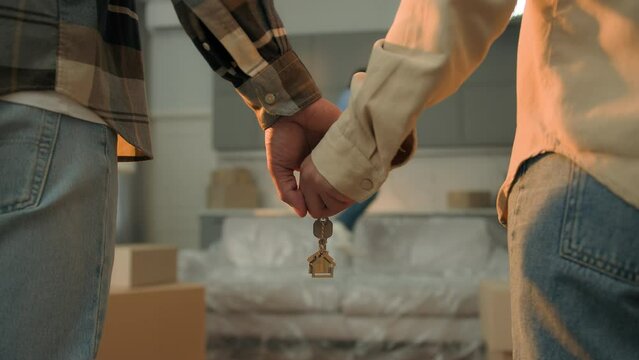 Close up couple hands holding keys buying house own apartment child kid boy son jumping on couch african american parents hold key of new home moving day relocation real estate purchase loan mortgage
