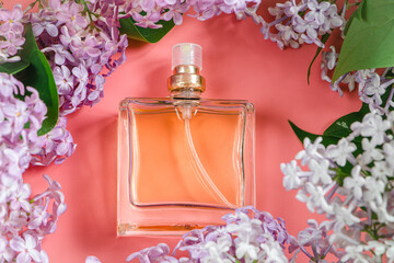 Perfume bottle and lilac flowers on pink background.
