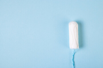 Hygienic cotton tampon on blue background. Feminine menstrual hygiene products.