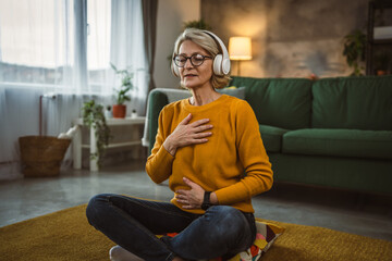 Obraz premium Mature blonde woman practice guided meditation manifestation at home