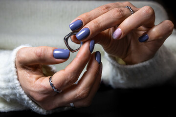 Woman's hands with blue manicure holding eyeglasses