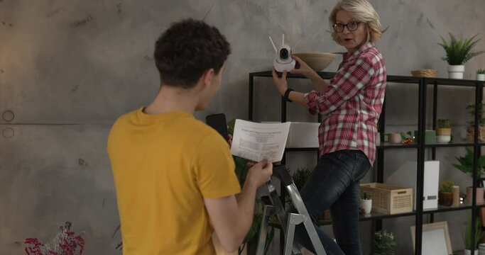Mother and son adjust and install home cctv video surveillance camera