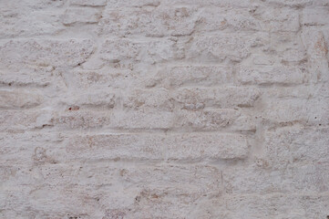 Closeup of old weathered white brick wall covered with lime