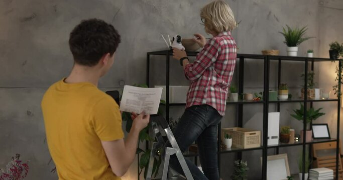 Mother and son adjust and install home cctv video surveillance camera