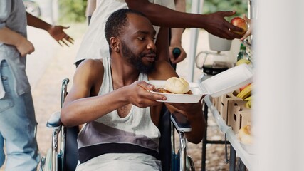 Free meals and fruits are given to a wheelchair-bound african american man in need. Handicapped,...