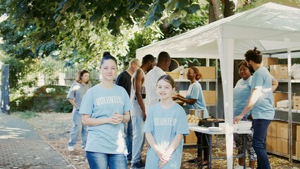 Portrait of a woman and daughter taking part in food bank program to fight hunger. Blue-shirted...