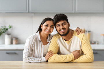 Portrait of loving young indian couple posing together at kitchen