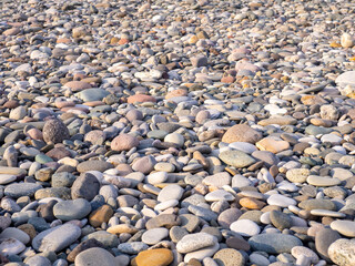 Gray sand and stones on the beach. Stone in the foreground.   Sea coast soil.