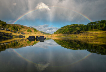 A complete rainbow and its reflection in the river