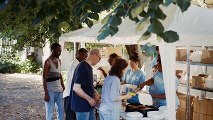 Volunteers serving free food to the needy at an outdoor event. This non-profit organization offers...