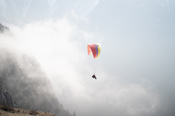 Paraglider soaring above misty mountain slopes