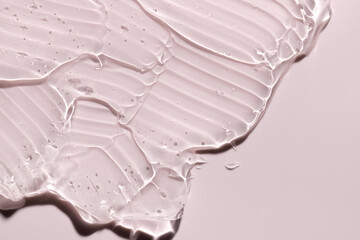 Transparent liquid gel on pink background. Cosmetic skincare product texture. Face cream, body lotion swipe swatch