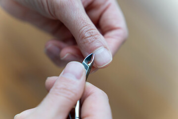 women's hands do manicures by trimming cuticles with nail clippers