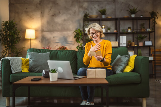 one mature woman open box presents and read card while on video call