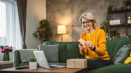 one mature woman open box presents and read card while on video call