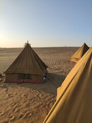 Campement de tente en plein milieu d'un désert, soleil couchant, reflet de lumière, camping entre amis, splot indien incourtounable, plaisir détente touristique, que du sable à l'horizon  - obrazy, fototapety, plakaty