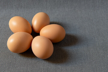 Fresh brown chicken eggs on grey background.
