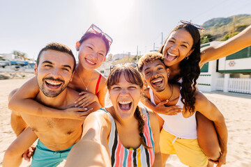 Diverse group of people having fun taking selfie portrait together with phone enjoying summer vacation in the beach. Friendship and holidays concept. - obrazy, fototapety, plakaty