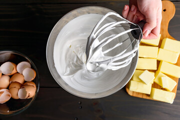 Hand Holding a Stand Mixer Whisk Attachment Covered in Meringue: Woman's hand holding a wire whip...