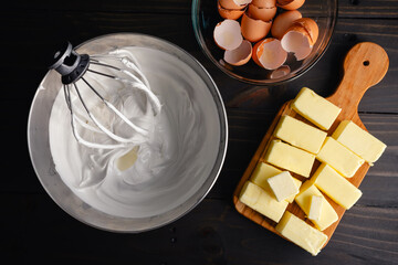 Mixing Bowl Filled with Meringue Next to Sticks of Butter: Wire whisk attachment placed in a bowl...