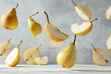 Healthy snack ripe pears slices levitating on a white wooden table against a gray wall packed with vitamins