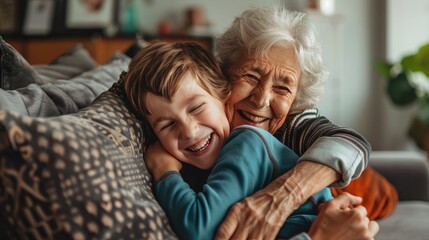 Happy boy hugging and having fun with her grandmother in their sofa at home, bonding moment of a cute little boy with his joyful grandma. Family