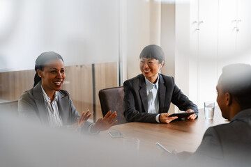 In a corporate office, a diverse group of multi-ethnic businesswomen and businessmen gather for a...