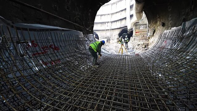 Worker carries ribbed iron in subway tunnel construction