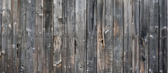 Fototapeta premium An upclose view of a grey wooden fence constructed from wooden planks, creating a beautiful pattern against the backdrop of green grass