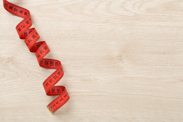 Measuring tape on wooden background, top, view