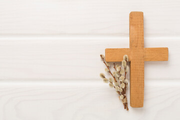 Cross with willow branches on wooden background, top, view. Palm Sunday concept