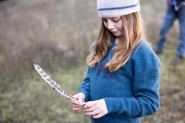 Girl holding wild turkey feather in nature