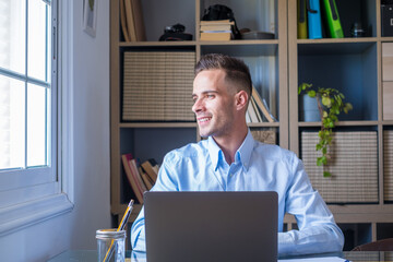 Fototapeta premium Caucasian reflexive looking at laptop screen, reflexing on work, businessman independent working in a difficult project. Male person preparing at home in the office indoor..
