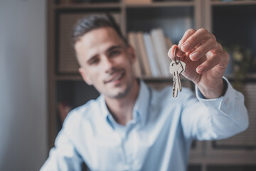 Focus on bunch of keys from house flat apartment in hand of smiling male. Blurred portrait of...