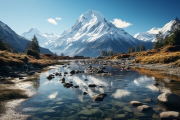 A river flows through a mountain valley with a snowy peak in the background - obrazy, fototapety, plakaty