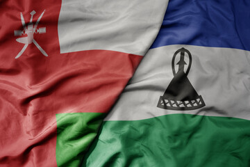 big waving national colorful flag of lesotho and national flag of oman.