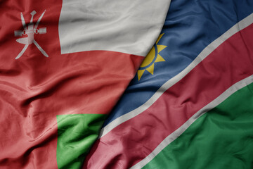 Fototapeta premium big waving national colorful flag of namibia and national flag of oman.